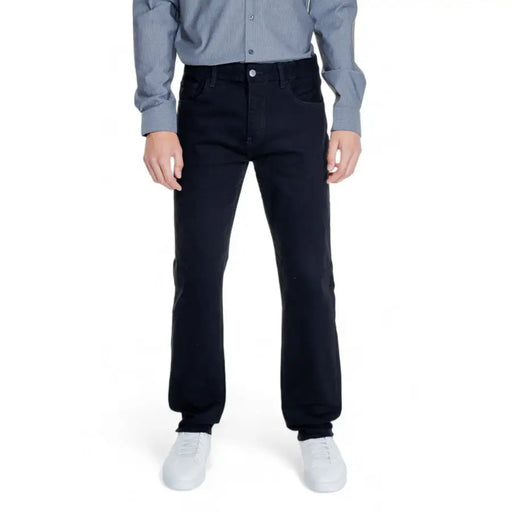 Men’s dark blue jeans paired with a light blue long-sleeved shirt and white sneakers