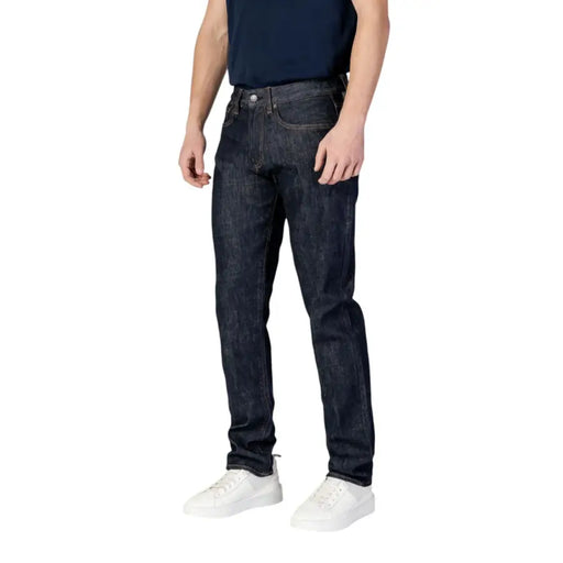 Dark wash slim fit jeans with a distressed look and white stitching.