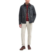 Men’s dark green quilted Barbour jacket with corduroy collar over red sweater and light pants