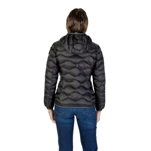 Woman wearing a black puffer jacket with hood and turtleneck, paired with blue jeans