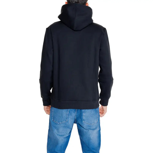 Men’s black hooded sweatshirt paired with blue jeans from Calvin Klein Jeans collection