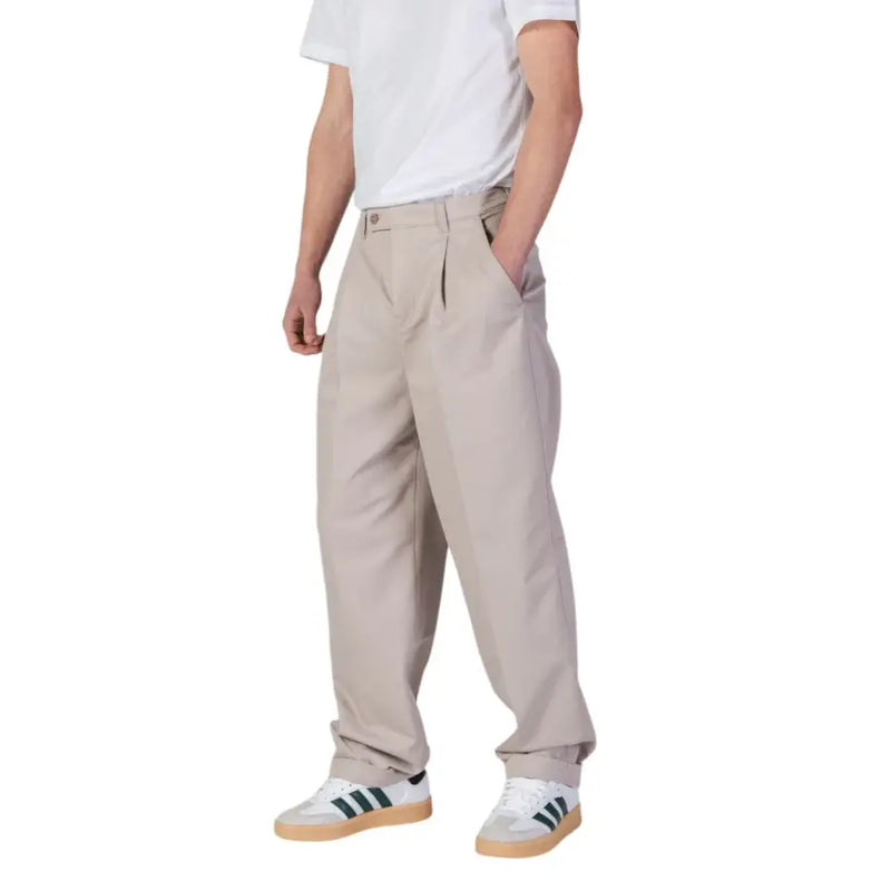Men’s beige pleated trousers paired with white and green striped sneakers from Calvin Klein Jeans