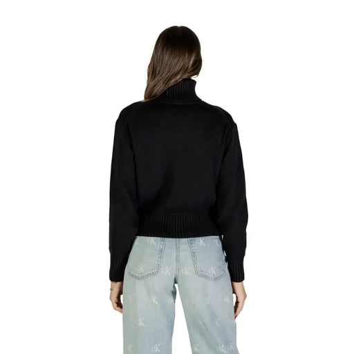 Women wearing Calvin Klein Jeans black printed turtleneck sweater with light wash jeans