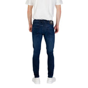 Dark blue slim-fit jeans paired with white sneakers in a men’s fashion display