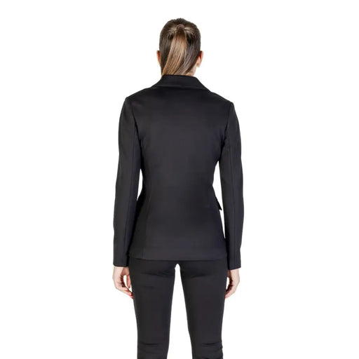 Woman wearing Guess long black V neck blazer and tailored slim-fit trousers for fall winter fashion