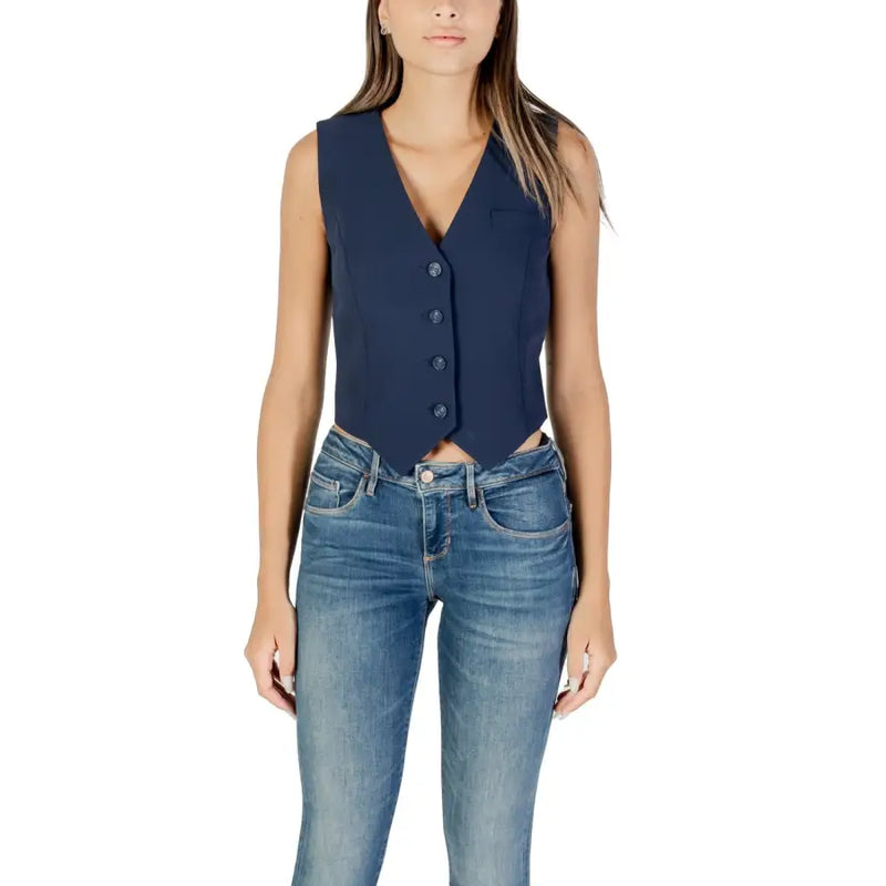 Woman wearing dark blue sleeveless V-neck button-up vest with blue jeans