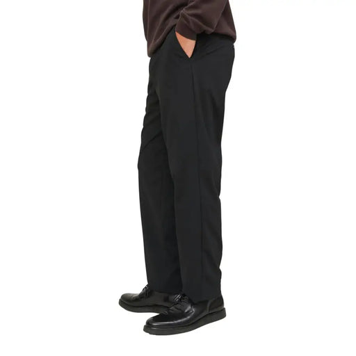 Men’s black loose-fit trousers paired with a brown sweater and black dress shoes