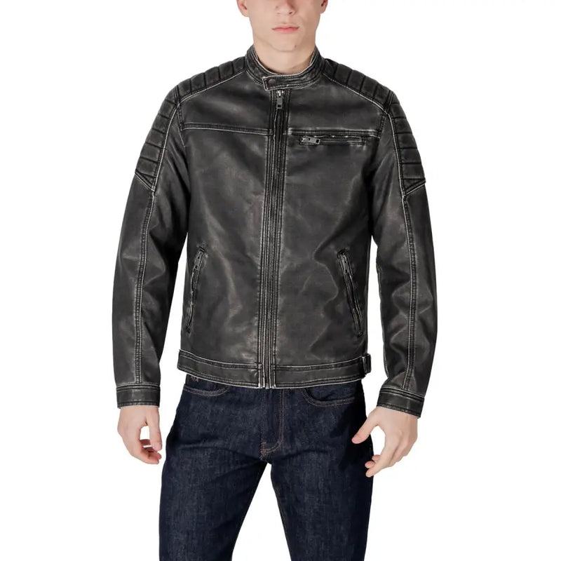 Men’s distressed black faux leather biker jacket with quilted shoulders and white stitching over dark wash jeans