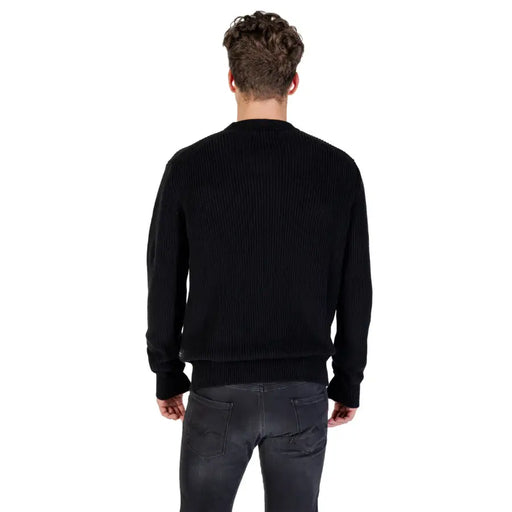 Male model wearing Black Ribbed Knit Sweater and Gray Jeans in a casual setting