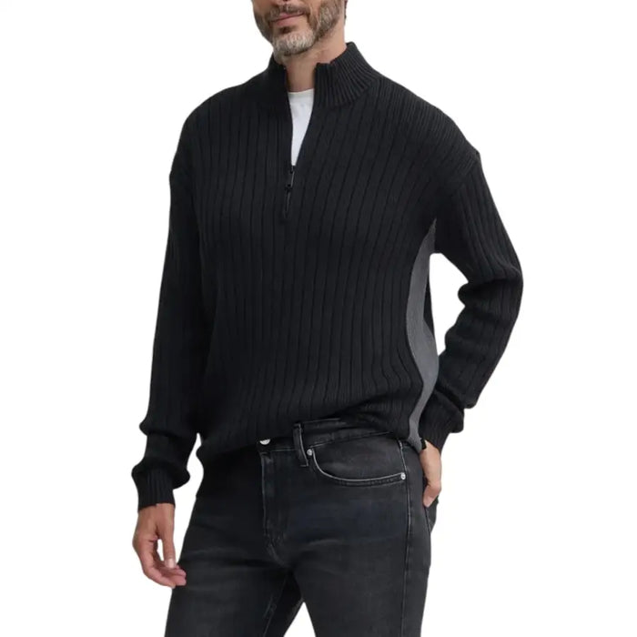 Man wearing black ribbed knit quarter-zip sweater and dark jeans displayed in product listing