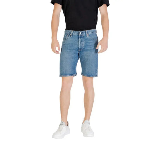 Man wearing denim shorts and white sneakers showcasing casual summer fashion