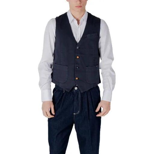 Man wearing a navy vest over a white shirt in a stylish ensemble