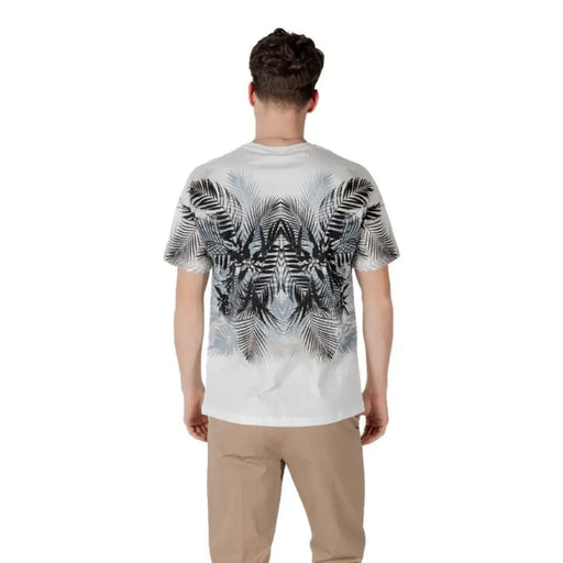 Man wearing a white T shirt with palm leaf pattern and khaki pants