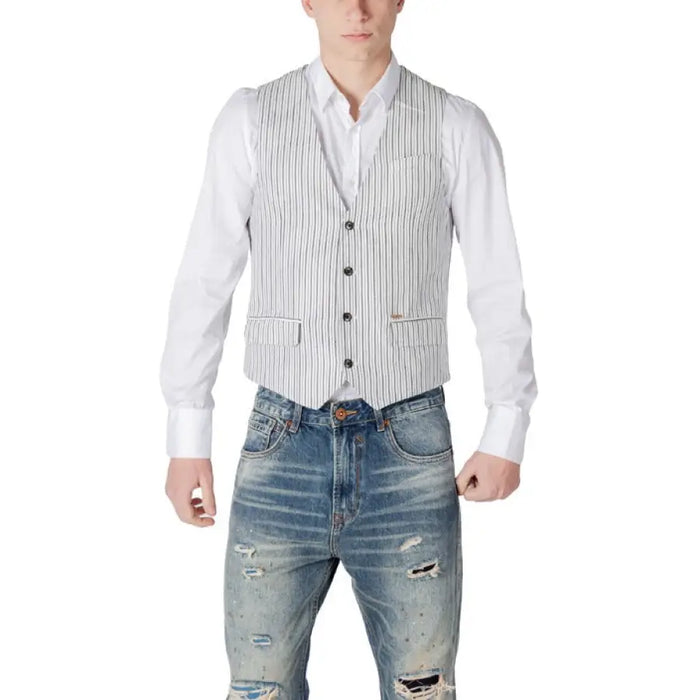 Man wearing a stylish striped vest paired with ripped jeans in a trendy outfit