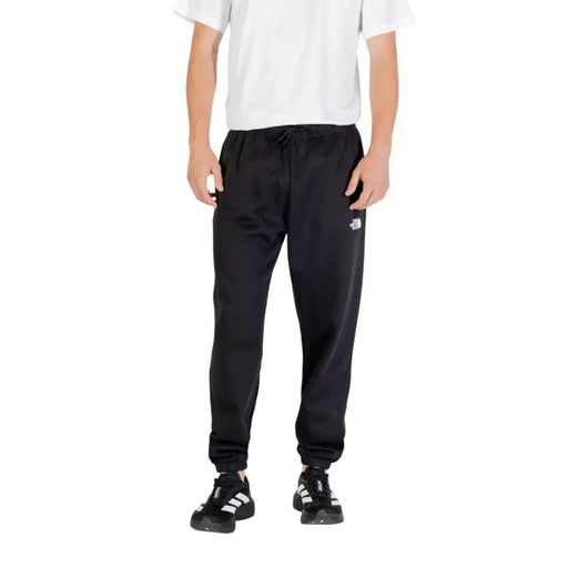 Men’s black athletic sweatpants with white logo and striped black and white sneakers