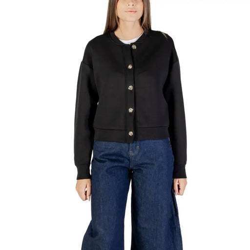 Black long buttoned cardigan with silver buttons paired with wide-leg blue jeans for women