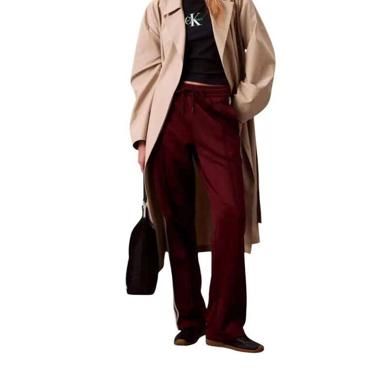 Woman wearing beige trench coat black Calvin Klein T-shirt and Bordeaux Lace Trousers