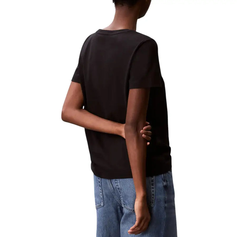 Woman in black Calvin Klein V-neck cotton T-shirt and blue jeans with crossed arms