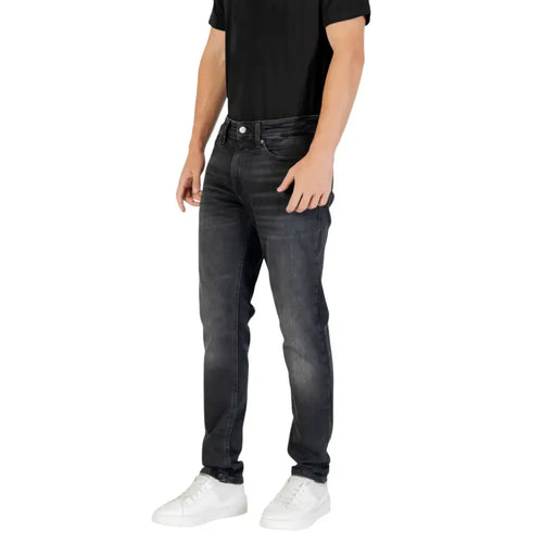Black slim fit jeans with white stitching and pockets, made of denim material.