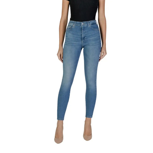 Light wash skinny jeans on a woman paired with a black top and nude heels from Tommy Hilfiger