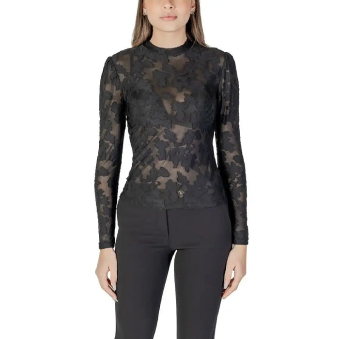Woman wearing a black floral lace long sleeve top paired with black pants