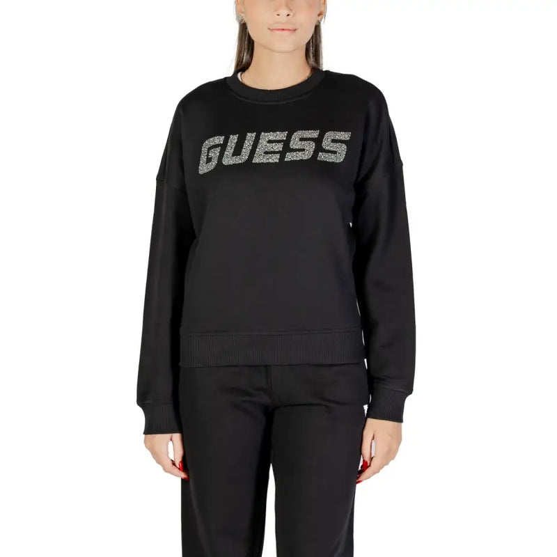 Woman wearing a black long-sleeved Guess sweatshirt with silver glitter logo and matching pants