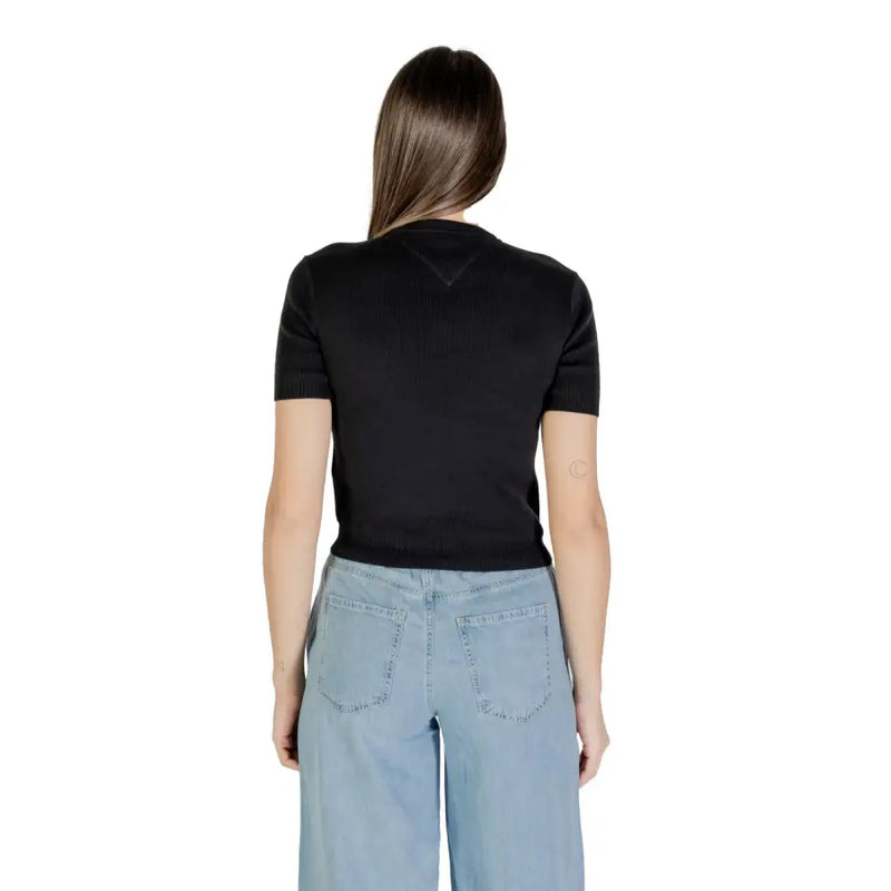 Woman wearing black organic cotton round neck T shirt and light blue wide-leg jeans