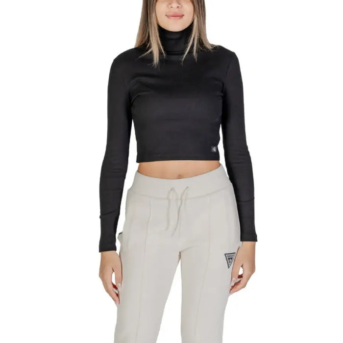 Woman wearing a black turtleneck crop top and light-colored sweatpants