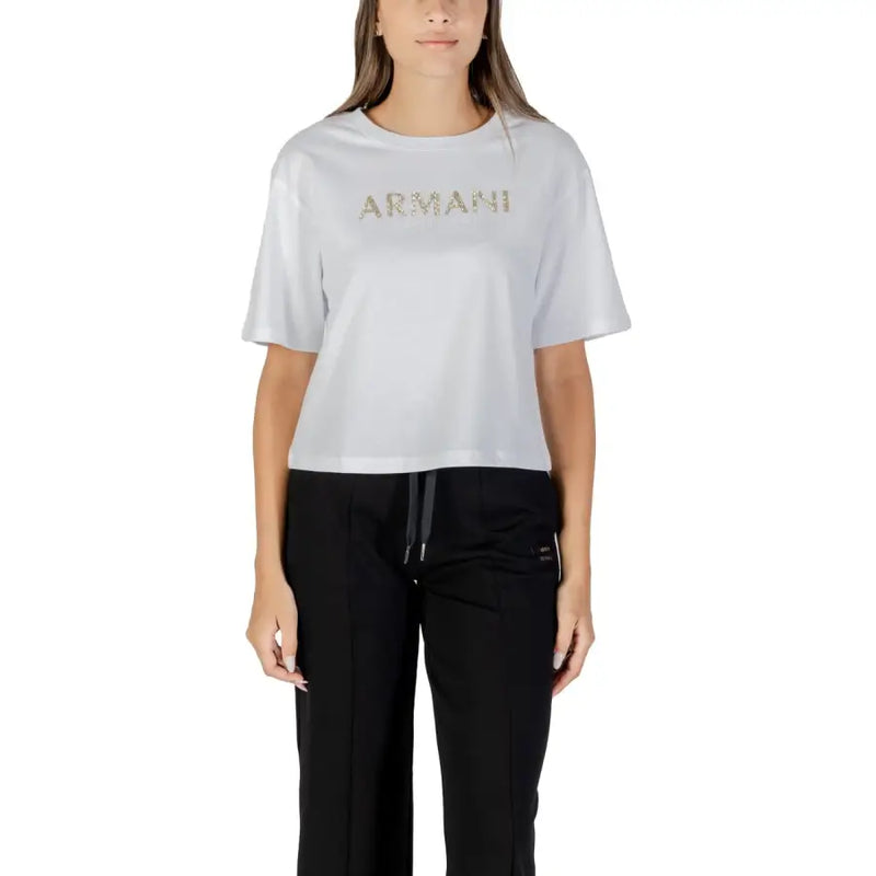 Woman wearing light grey Armani Exchange T shirt with gold lettering and black track pants