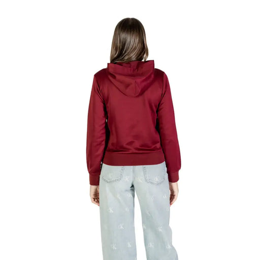 Woman wearing a maroon hoodie and light-wash wide-leg jeans in Calvin Klein Bordeaux sweatshirt