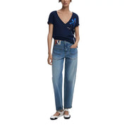 Woman wearing navy blue V-neck top with floral embroidery and light-wash jeans