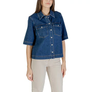 Woman wearing a classic blue short sleeve cotton shirt and light-colored pants