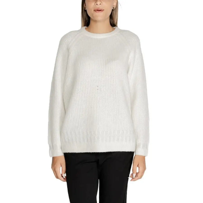 Woman wearing a white knit sweater and black pants for the White Knit Sweater with Black Pants product
