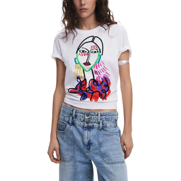 Woman wearing a white T shirt with a colorful face graphic and light blue jeans