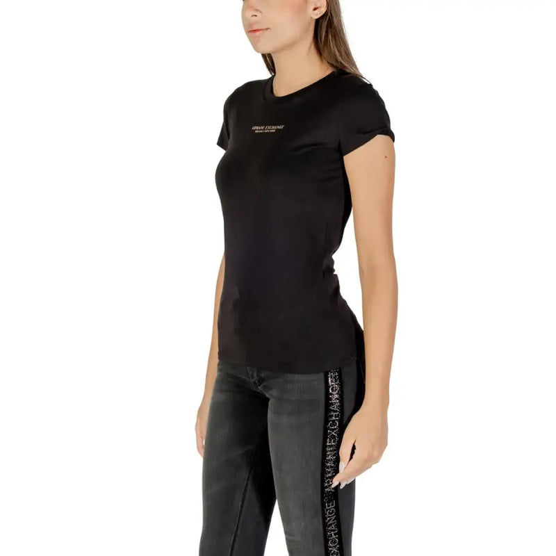 Woman wearing Armani Exchange black printed crew neck T-shirt with rolled sleeves and black jeans with side stripe