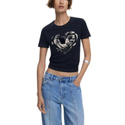 Woman wearing Desigual black print short sleeve round neck T-shirt with white heart graphic and light wash jeans