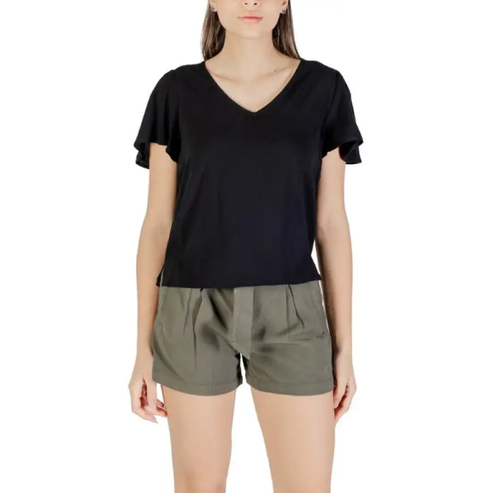 Woman wearing black V-neck flutter-sleeve top and green shorts in product display