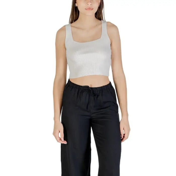 Woman wearing cropped tank top and black pants standing confidently