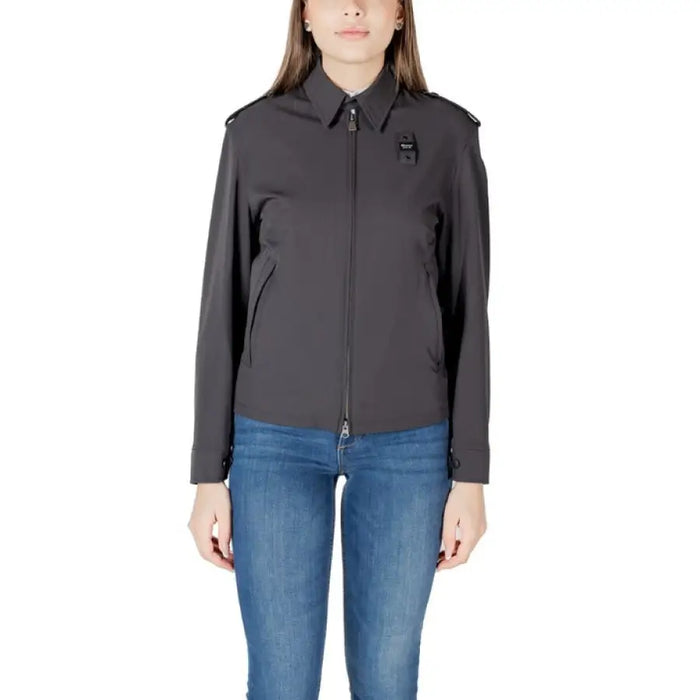 Woman wearing a dark gray collared jacket paired with blue jeans