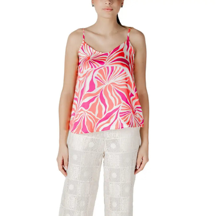 Woman wearing floral print camisole and white pants showcasing stylish summer fashion