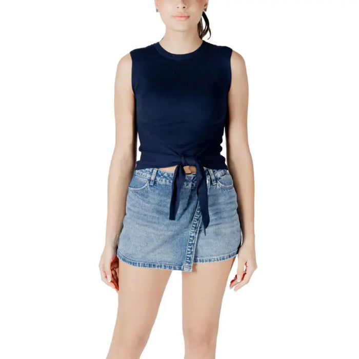 Woman wearing navy tie-front tank top and denim mini skirt showcasing casual style