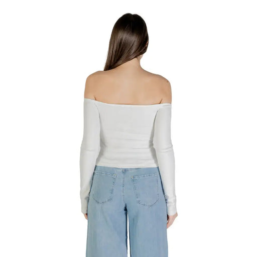 Woman wearing a white off-the-shoulder long-sleeved top with wide-leg jeans