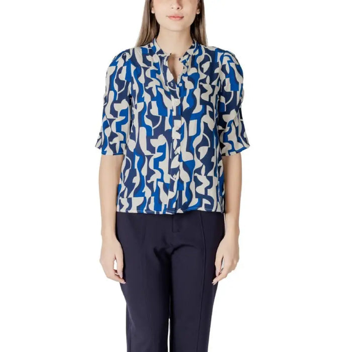 Woman wearing a blue and white patterned blouse with dark pants