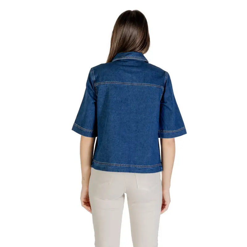 Woman wearing classic blue short sleeve cotton denim shirt with light-colored pants