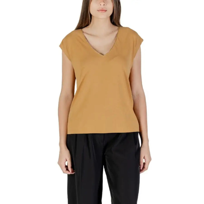 Woman wearing a tan V-neck top and black pants, showcased in the Orange V Neck Top for Women product image