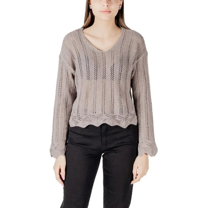 Woman wearing taupe open-knit long-sleeved sweater with scalloped hem