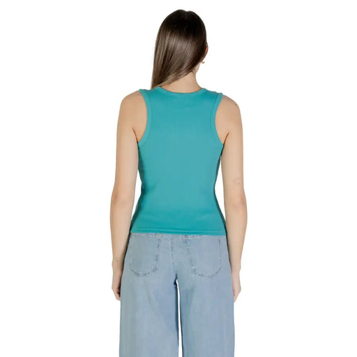 Woman wearing Calvin Klein Jeans teal ribbed tank top with light blue wide-leg jeans