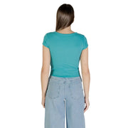 Woman wearing teal short-sleeve Calvin Klein Jeans T-shirt with light blue wide-leg jeans