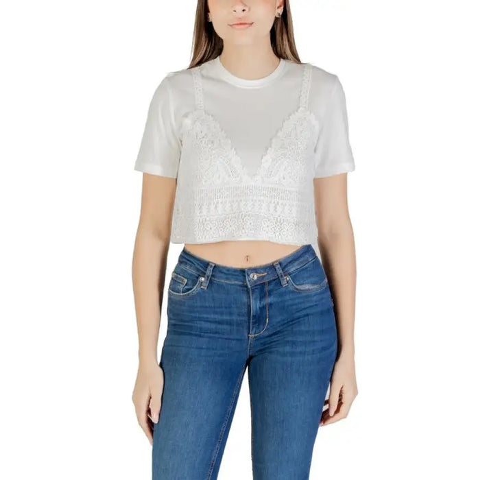 Woman wearing a white layered top and blue jeans showcasing stylish casual attire