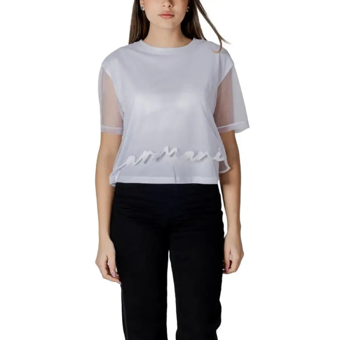 Woman wearing a white sheer-sleeved top paired with black pants, showcasing a stylish outfit